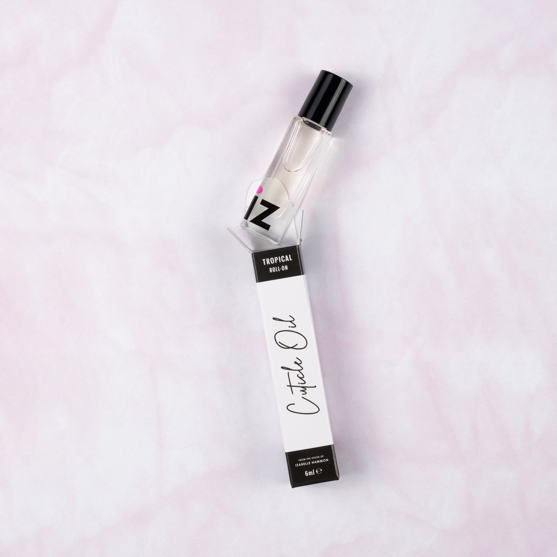 Cuticle oil roller bottle and packaging on a light pink background