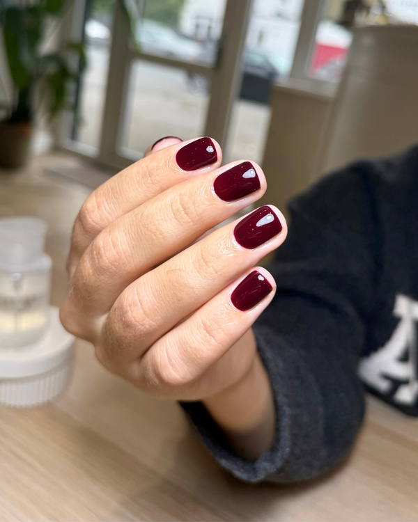 Hand with burgundy nail gel a nail salon. Colour is Obsession from Calgel and Pro Colour.
