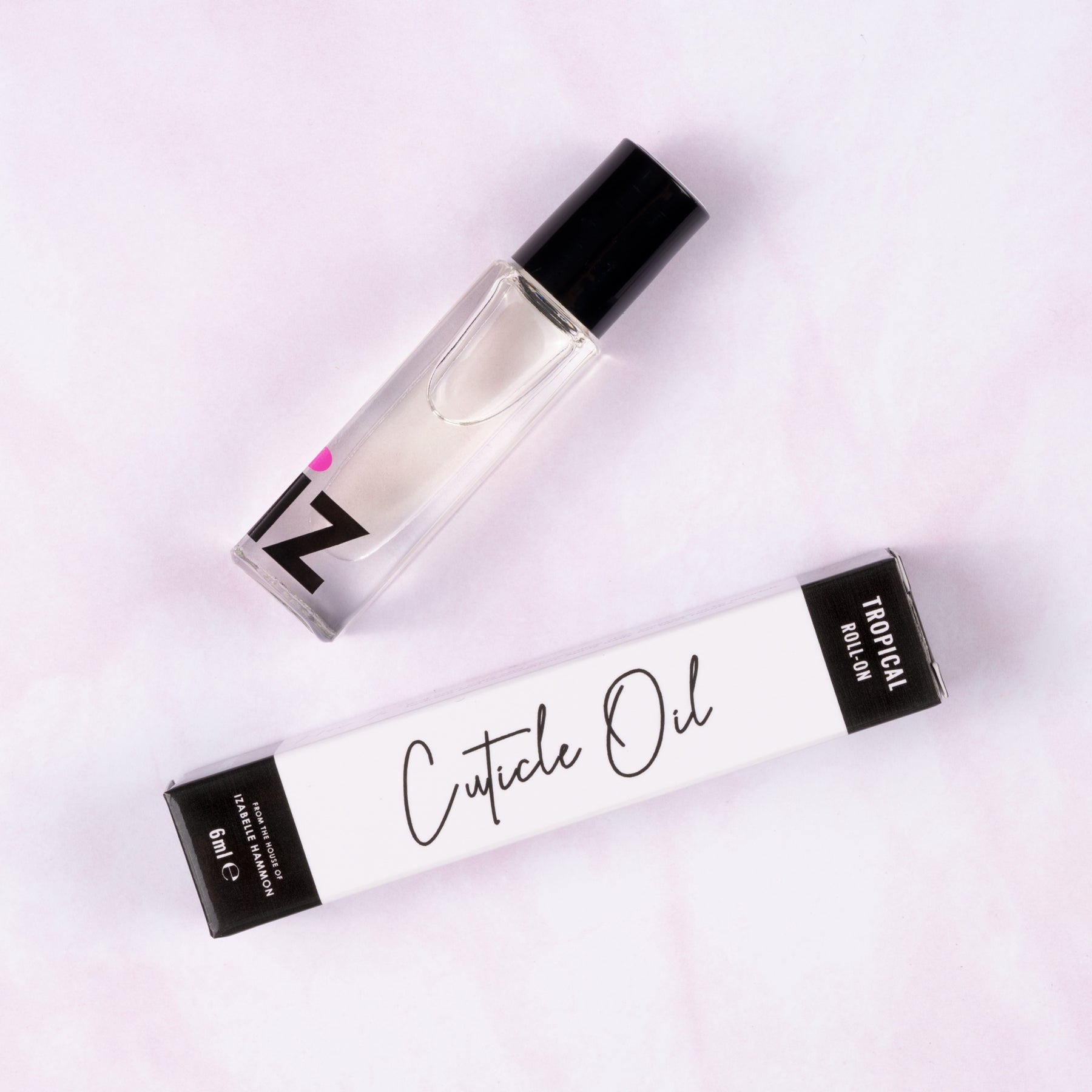 Roll on cuticle oil bottle and packaging on a light pink background